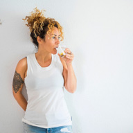 Woman leaning on a wall drinking