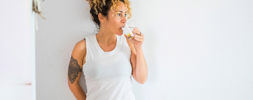 Woman leaning on a wall drinking