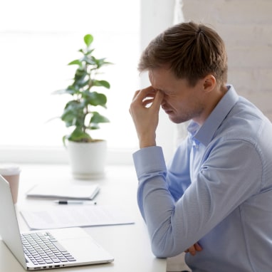 Man at desk rubbing eyes