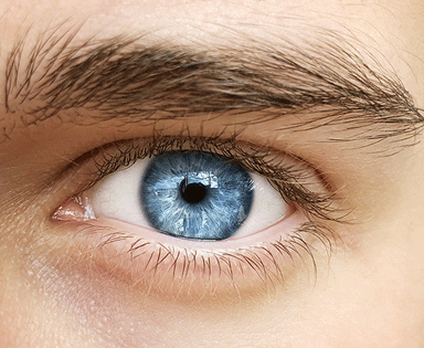 Image shows man sitting at desk looking down at phone with strained eyes