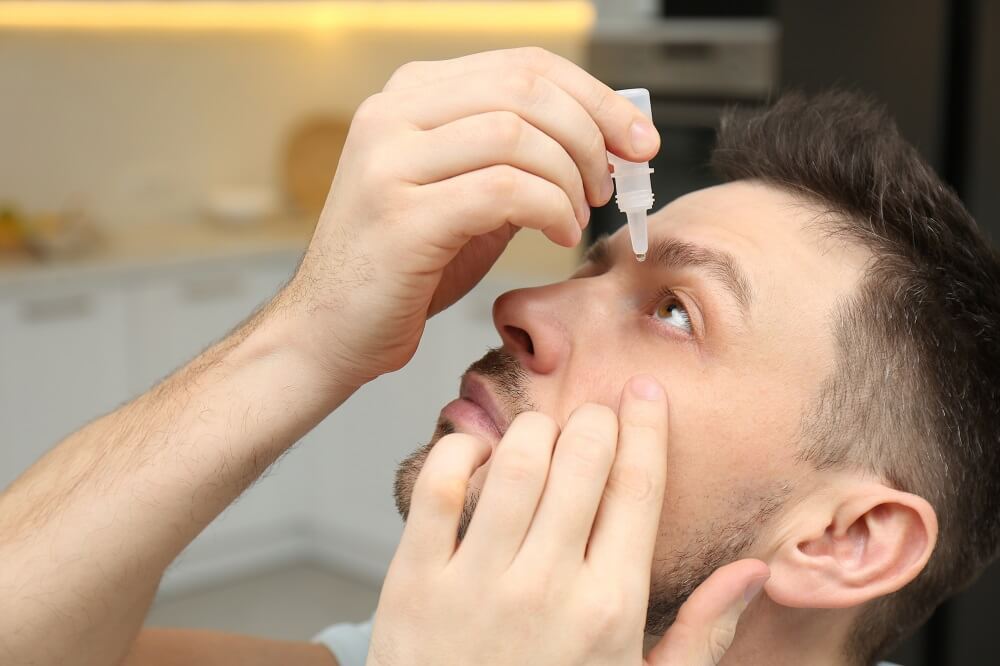 Image shows man putting in eye drops