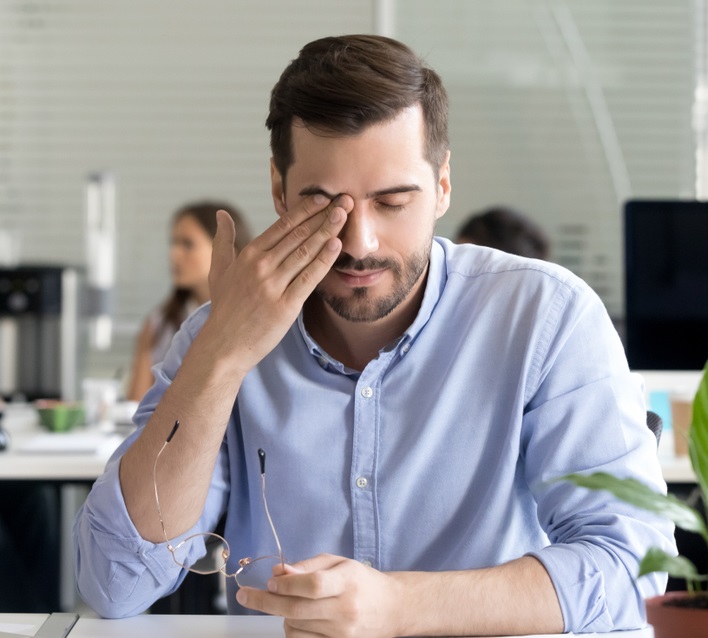 Man in the office rubbing his eye